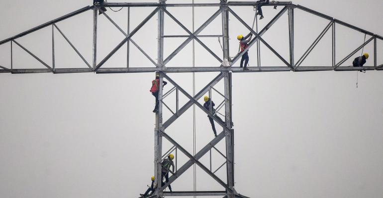 Technicians work on an unconnected transmission tower