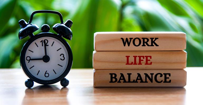 Alarm clock pointing at 9am with work life balance text on wooden blocks