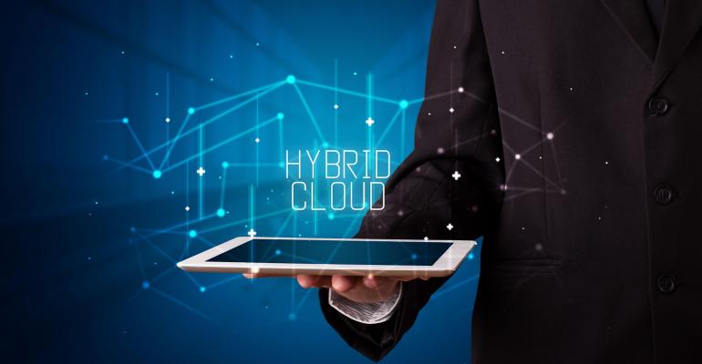 person holding a notebook with "hybrid cloud" spelled out above it
