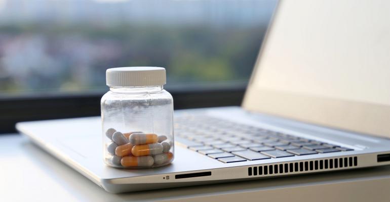 bottle of pills sitting on a laptop
