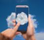 Hands holding a smartphone with images of clouds