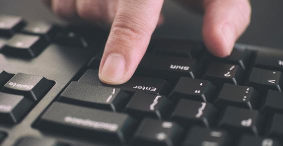 Person typing on a keyboard and pressing Enter key