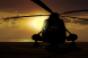 Image shows a military helicopter on carrier ship at sunset.