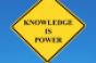 yellow road sign reading KNOWLEDGE IS POWER blue background