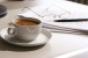 coffee in cup with papers glasses and pen in background