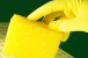 Gloved hand using yellow sponge to clean a surface